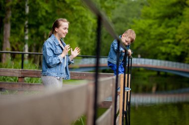 Anne Çocuk suya düşecek yaşıyor. Küçük bir çocuk parkta bir köprüden tırmanıyor. Boğulma tehdidi. Çocuklar için tehlike