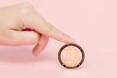 Kadın, pembe bir sırtında parıldayan yeni altın bitcoin ile el ele tutuşuyor.