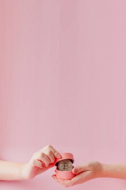 Pembe bir sırt deliğinde Bitcoin 'i pembe hediye kutusunda tutan kadının elleri.