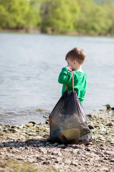 Αποθήκευση έννοια περιβάλλον, ένα μικρό αγόρι μαζεύοντας σκουπίδια και PL — Φωτογραφία Αρχείου