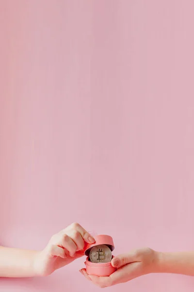 Manos de mujer sosteniendo bitcoin en caja de regalo rosa en un backgro rosa — Foto de Stock