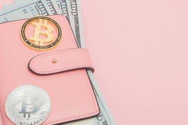 Pembe arka planda fotokopi alanı olan pembe bir cüzdanda Bitcoin ve dolar
