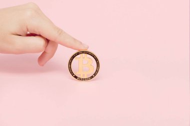 Parlayan yeni altın bitcoin pembe bir arka plan, metin için kopya yer tutan el kadındır