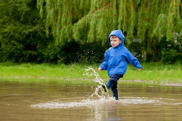 Portrait d'un garçon mignon jouant avec un bateau fait main. maternelle garçon voguant un bateau jouet au bord de l'eau dans le parc — Photo