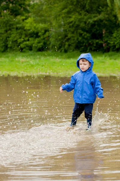 Portrait d'un garçon mignon jouant avec un bateau fait main. maternelle garçon voguant un bateau jouet au bord de l'eau dans le parc — Photo