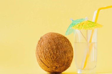 Sarı arka planda bir pipet ile taze Hindistan cevizi kokteyli, kopya alanı