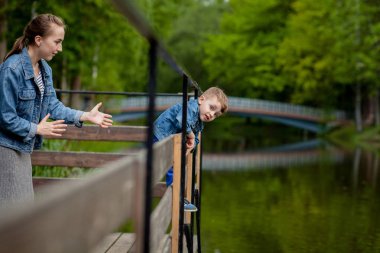 Anne Çocuk suya düşecek yaşıyor. Küçük bir çocuk parkta bir köprüden tırmanıyor. Boğulma tehdidi. Çocuklar için tehlike