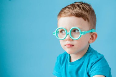 Mavi arka plan üzerinde oyuncak gözlük küçük bir çocuk portresi