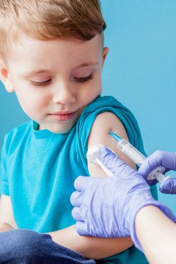 Aşılama konsepti. Mavi arka planda sevimli küçük çocuk aşık kadın doktor, çekim
