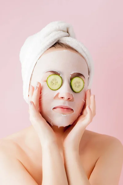 Mulher bonita está aplicando uma máscara de tecido cosmético em um fa — Fotografia de Stock
