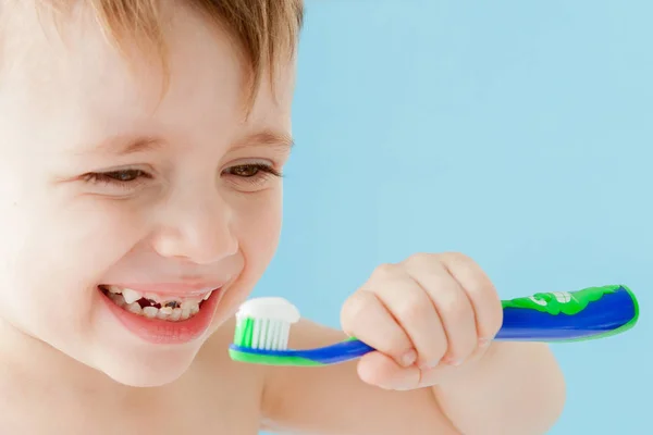 Retrato de niño pequeño con cepillo de dientes sobre fondo azul — Foto de Stock