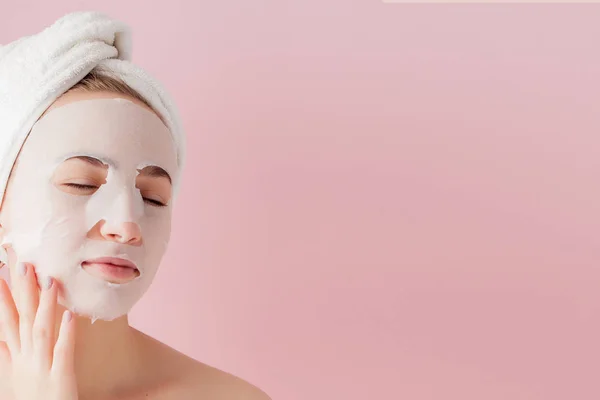 Beautiful young woman is applying a cosmetic tissue mask on a fa — Stock Photo, Image