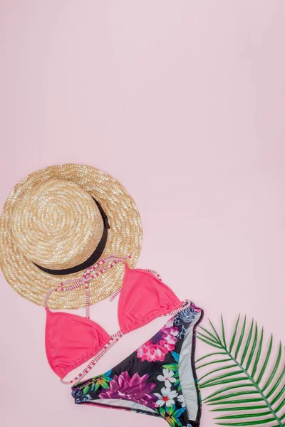 Cappello, costume da bagno e occhiali da sole su sfondo rosa. Vista dall'alto, piatta — Foto Stock