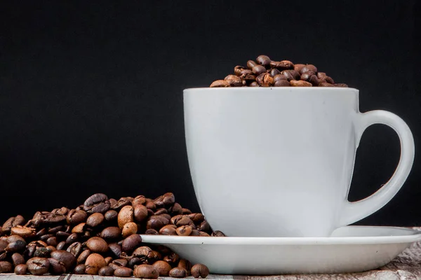 Black coffee in white cup and coffee beans on black background. Top view, space for text — Stock Photo, Image