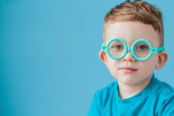 Retrato de um menino em óculos de brinquedo em fundo azul — Fotografia de Stock