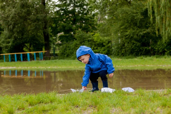 Portrait d'un garçon mignon jouant avec un bateau fait main. maternelle garçon voguant un bateau jouet au bord de l'eau dans le parc — Photo