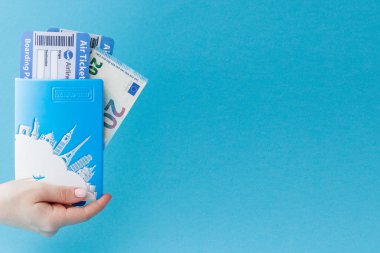 Mavi arka planda kadın el pasaport, Euro ve hava bileti