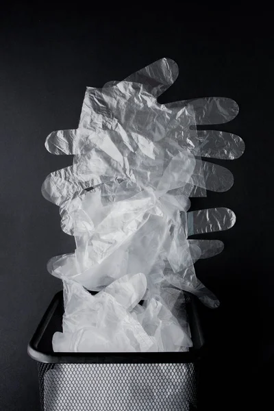 Plastpåse med handtag, handskar i soptunnan på en svart bakgrunds — Stockfoto