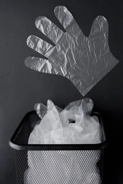 Bolsa de plástico con asas, guantes en la papelera sobre un fondo negro —  Fotos de Stock