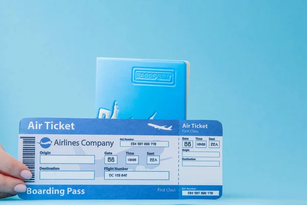 Paspoort en vliegticket in Woman hand op een blauwe achtergrond. Trav — Stockfoto