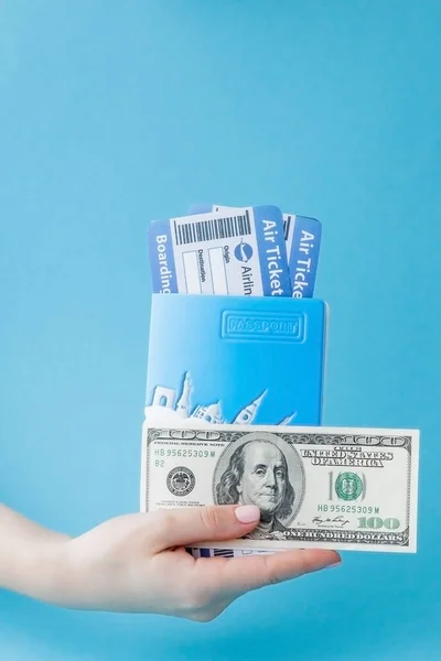 Διαβατήριο, δολάρια και αεροπορικό εισιτήριο σε γυναίκα χέρι σε μια μπλε βάση — Φωτογραφία Αρχείου