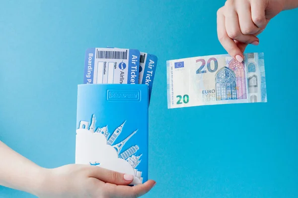 Passport, euro and air ticket in woman hand on a blue background — Stock Photo, Image