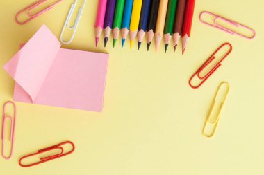 Metin alanı ile okul konseptine geri dönün. Üst görünüm. Boşluk Kopyala. Okul ofisi malzemeleri. Renkli Kırtasiye ile yaratıcı masa. Renkli kağıt klip. Sarı arka planda okul malzemeleri. Ofis Masası