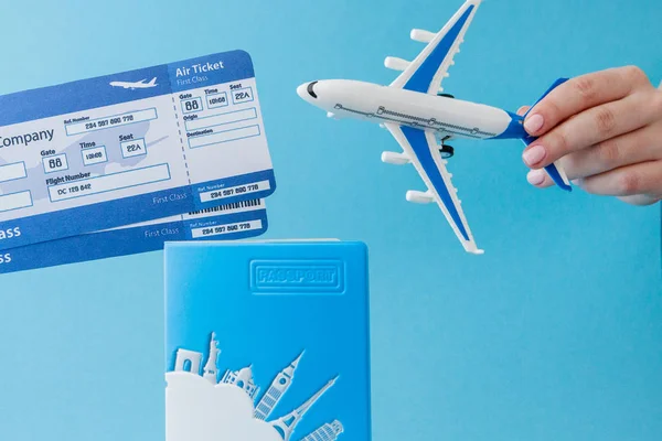 Paspoort, vliegtuig en lucht ticket in de vrouw hand op een blauwe backgroun — Stockfoto