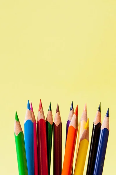 Fila de lápices de colores sobre fondo amarillo — Foto de Stock