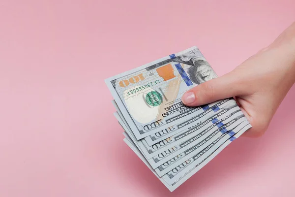 Pilha de notas de dólar na mão feminina sobre fundo rosa — Fotografia de Stock