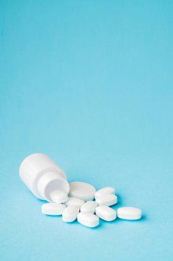 Hap hap şişesi üzerinde mavi arka plan dışarı dökülmesini kapatın. Tıp, sağlık sigortası veya eczane konsepti