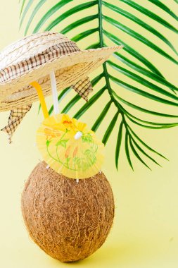 Sarı arka planda bir pipet ile taze Hindistan cevizi kokteyli