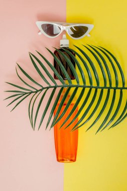 Parlak kare sarı ve pembe arka planda şişe güneş kremi. Denizde tatil konsepti, yaz zamanı. Üst görünüm, düz yatıyordu, Minimalizm, kopya alanı