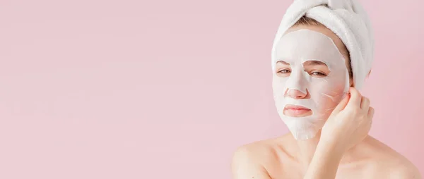 Wanita muda yang cantik menerapkan masker jaringan kosmetik pada sebuah fa — Stok Foto