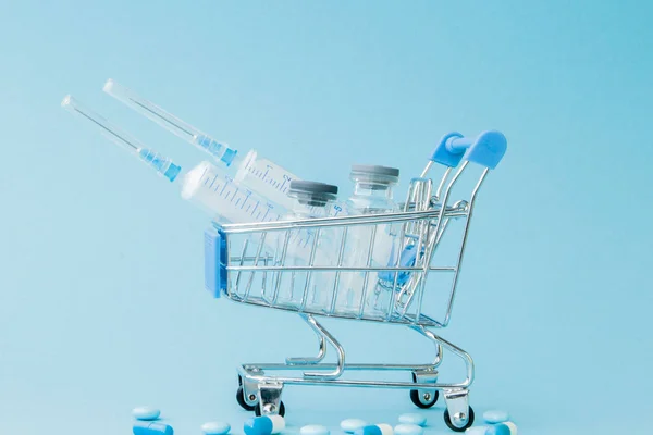 Hapları ve mavi backgrou üzerinde alışveriş arabası tıbbi enjeksiyon — Stok fotoğraf