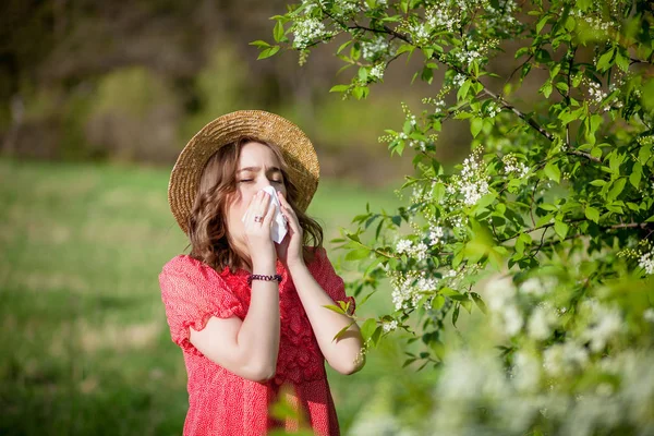 Young girl blowing nose and sneezing in tissue in front of bloom — Stock Photo, Image