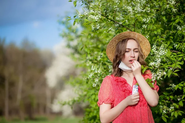 Ung flicka blåser näsa och nysningar i vävnad framför Blom — Stockfoto