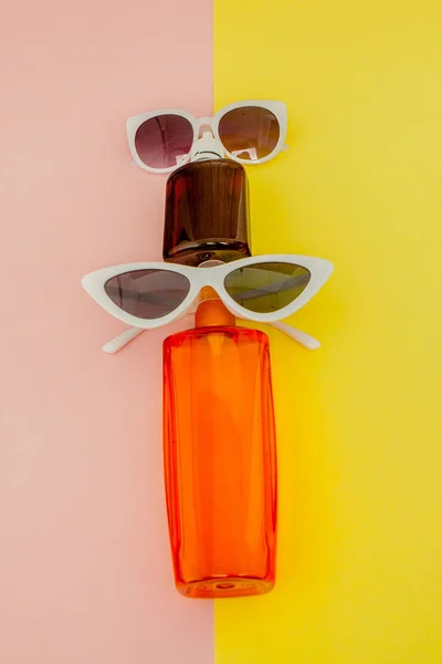 Flasche Sonnenschutz auf hellem quadratischen gelben und rosa Hintergrund. das Konzept des Seebades, Sommerzeit. Draufsicht, flache Lage, Minimalismus, Kopierraum — Stockfoto
