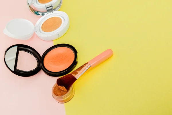 Make up prodotti versando su uno sfondo giallo brillante e rosa con spazio copia — Foto Stock