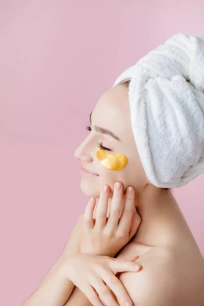 Porträtt av skönhetskvinna med ögonlappar på rosa bakgrund. Woman Beauty Face with Mask under ögonen. Vacker kvinna med naturlig makeup och Gold Cosmetics kollagen fläckar på fräsch ansiktshud — Stockfoto