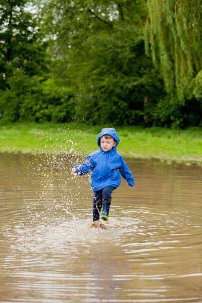 Portrait d'un garçon mignon jouant avec un bateau fait main. maternelle garçon voile un bateau jouet par le bord de l'eau dans le parc — Photo