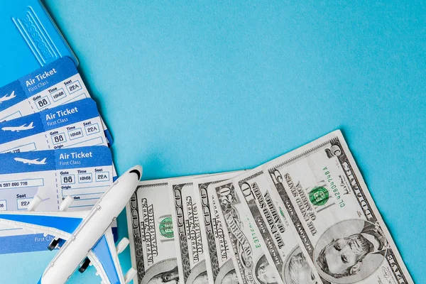 Passaporte, dólares, avião e bilhete de avião sobre fundo azul. Conceito de viagem, espaço de cópia — Fotografia de Stock