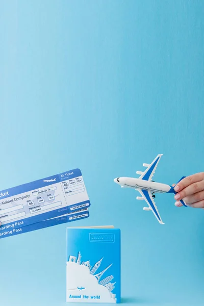 Passport, plane and air ticket in woman hand on a blue background. Travel concept, copy space