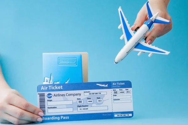 Paszport, samolot i bilet lotniczy w ręce kobiety na niebieskim tle. Koncepcja podróży, przestrzeń kopiowania — Zdjęcie stockowe