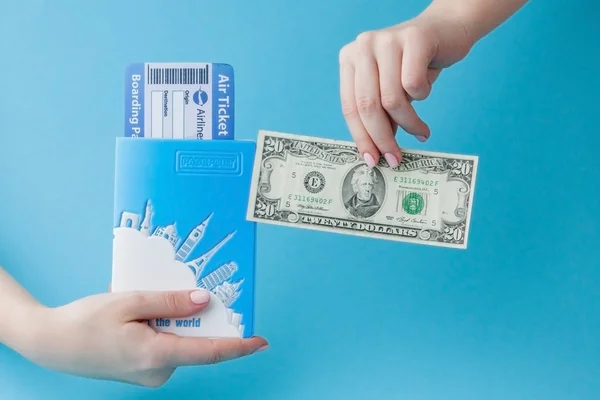 Paspoort, dollars en vliegticket in Woman hand op een blauwe achtergrond. Reis concept, kopieerruimte — Stockfoto