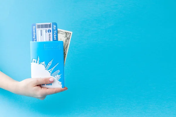 Paspoort, dollars en vliegticket in Woman hand op een blauwe achtergrond. Reis concept, kopieerruimte — Stockfoto