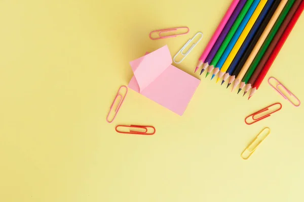 Back to school concept with space for text. Top view. Copy space. School office supplies.Creative desk with colourful stationery. Colored paper clip.School supplies on yellow background.Office desk