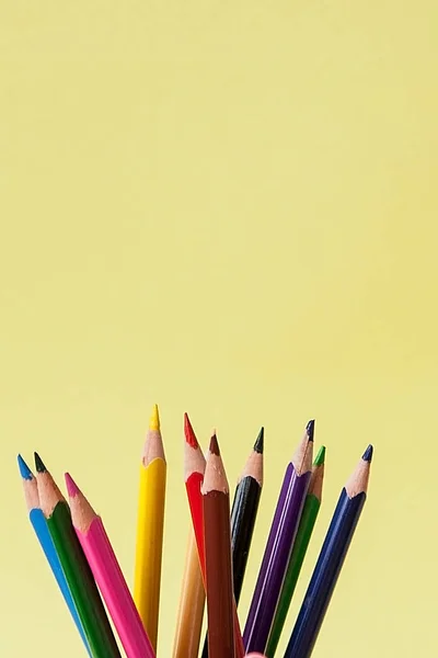 Fila de lápices de colores sobre fondo amarillo — Foto de Stock