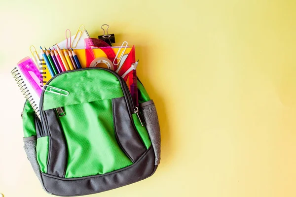 Flache Liegekomposition mit Rucksack und Schulpapier auf gelbem Hintergrund — Stockfoto