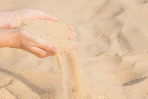 Arena fluyendo a través de las manos de la mujer en la playa — Foto de Stock